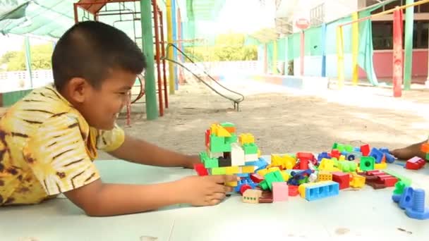 Poco lindo asiático chico jugando con plástico bloques de construcción en el parque — Vídeos de Stock