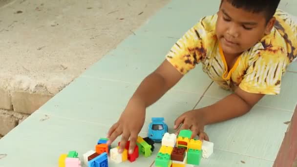 Маленький милий азіатський хлопчик грає з пластиковими будівельними блоками в парку — стокове відео