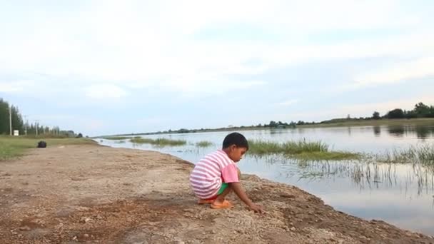 Lindo niño tirar piedra al río — Vídeo de stock