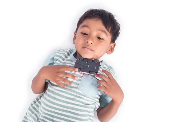 Lindo asiático pequeño niño jugar juguete coche y acostado en el suelo —  Fotos de Stock