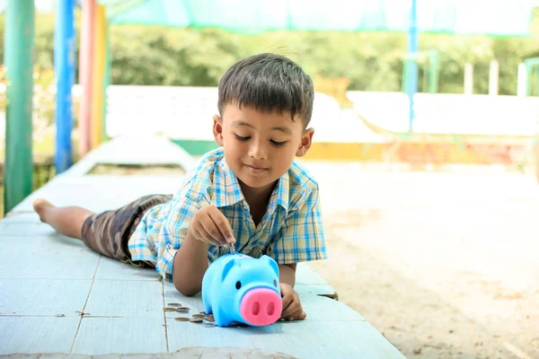 Милый азиатский мальчик экономит деньги в копилке свиньи — стоковое фото
