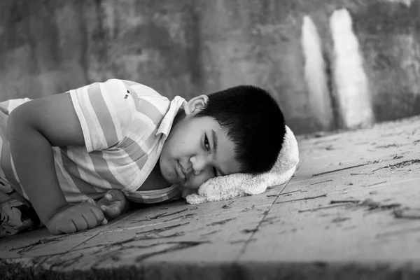 Бедный мальчик лежит на грязном полу. — стоковое фото
