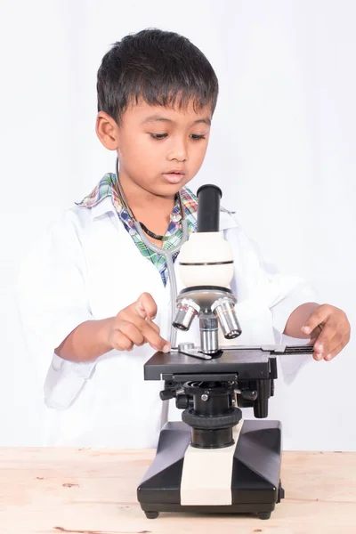 Милий азіатський маленький студент, що працює з мікроскопом — стокове фото
