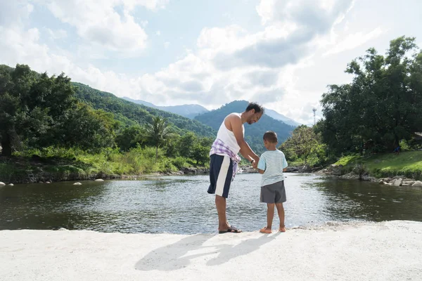 Тато і син годують рибу на річці — стокове фото