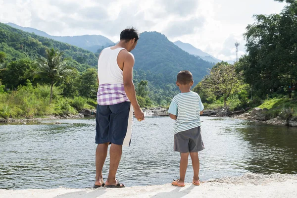 Тато і син годують рибу на річці — стокове фото