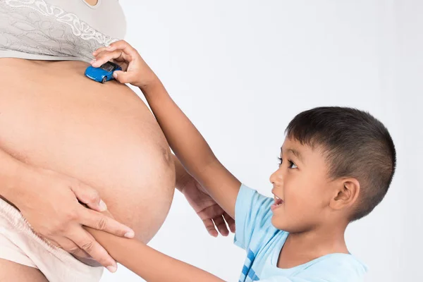 Frère utilisation jouet voiture jouer sur le ventre de maman, concept enceinte — Photo