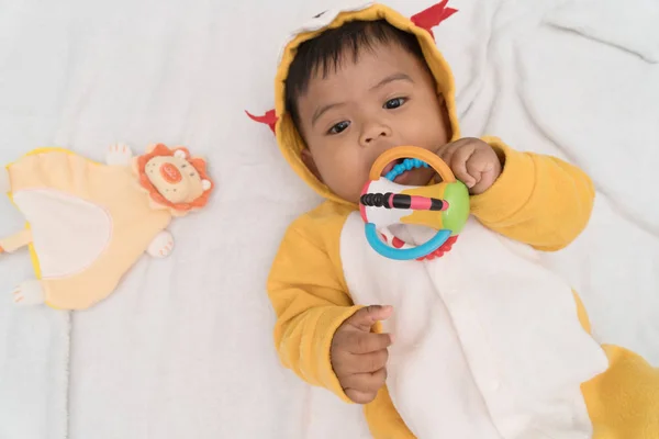 Lindo asiático bebé mintiendo en cama y jugar juguete, foco en juguete — Foto de Stock