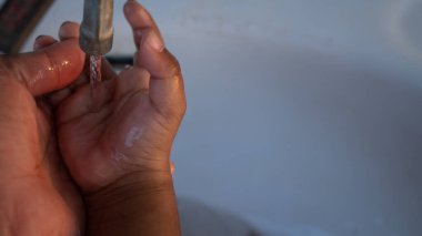 Küçük tatlı Asyalı çocuk elini yıkıyor.