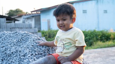 Küçük sevimli Asyalı çocuk taş yığınında oynuyor.