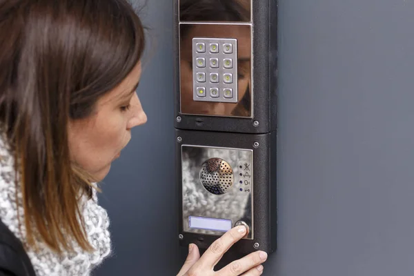 Mulher apertando o botão e falando no interfone — Fotografia de Stock