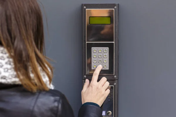 Mulher apertando o botão e falando no interfone — Fotografia de Stock