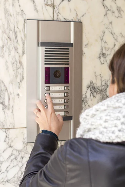 Mulher apertando o botão e falando no interfone — Fotografia de Stock