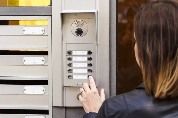 Mulher apertando o botão e falando no interfone — Fotografia de Stock