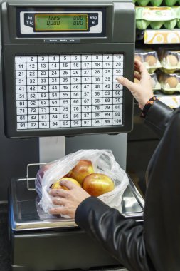 Kadın bir denge üzerinde süpermarkette elma tartı