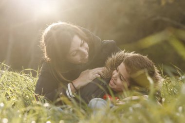 Anne ve oğlu günbatımında alanında oturup