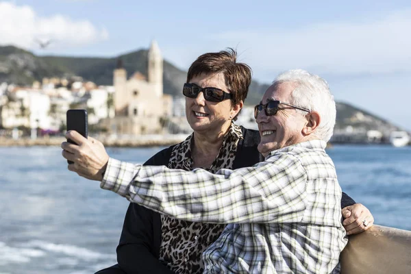 Два пенсионера пользуются мобильным телефоном в Ситжесе, Испания — стоковое фото