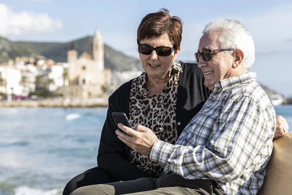 Два пенсионера пользуются мобильным телефоном в Ситжесе, Испания — стоковое фото