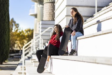 İki mutlu genç patenci merdivenlerde dinleniyor.