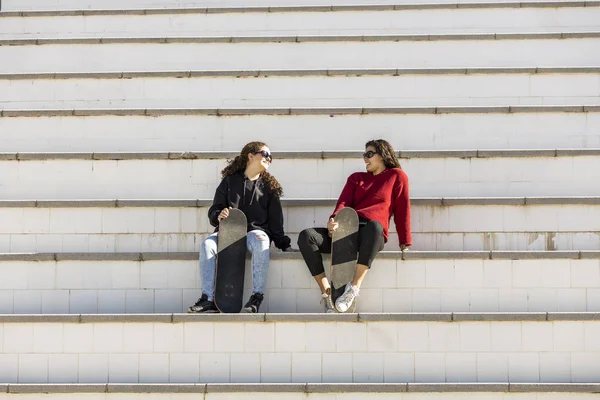 Zwei glückliche jugendliche Skater ruhen sich auf der Treppe aus — Stockfoto