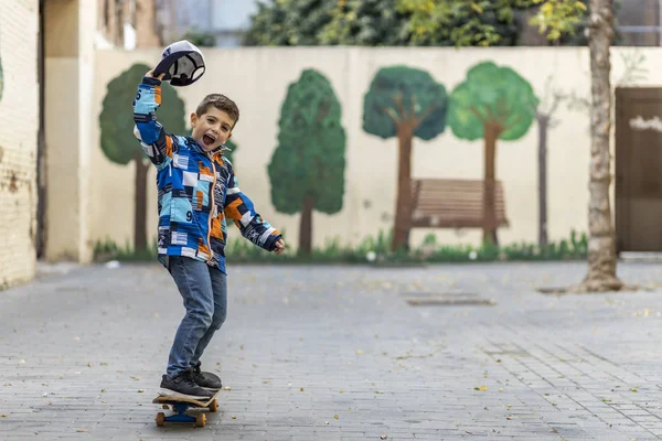 Criança eufórica montando em seu skate — Fotografia de Stock