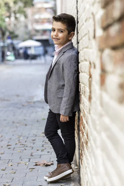 Moda mały dzieciak z cegły ściany tle — Zdjęcie stockowe