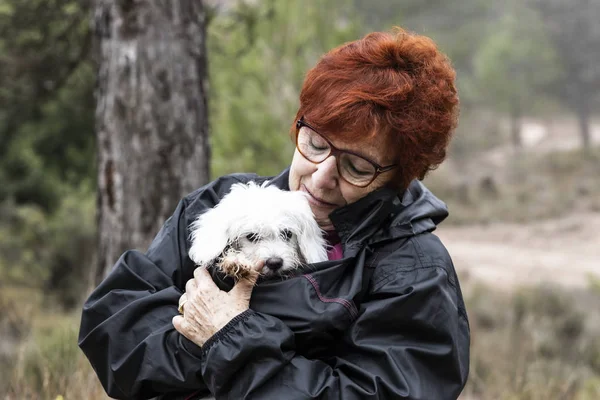 Elderly woman protecting a dirty and wet puppy from the cold — Stock Photo, Image