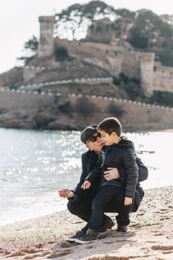 Büyükbaba ve torun kışın kumsalda eğleniyorlar.