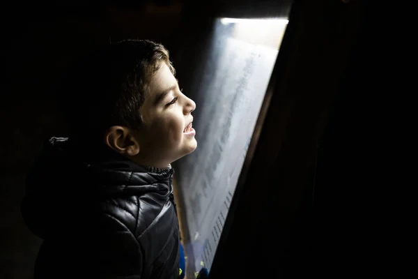 Liten pojke läser en affisch på natten — Stockfoto