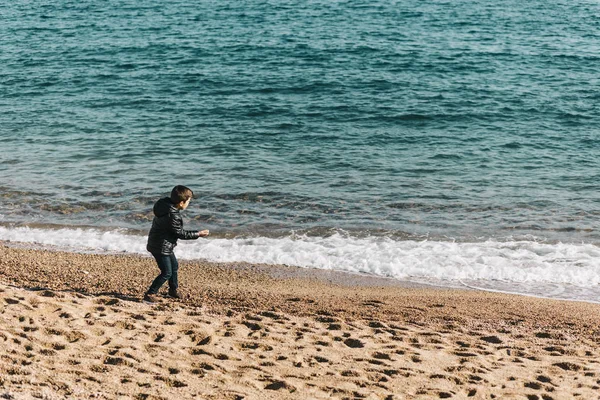 Cute kid throwing rocks at the ocean