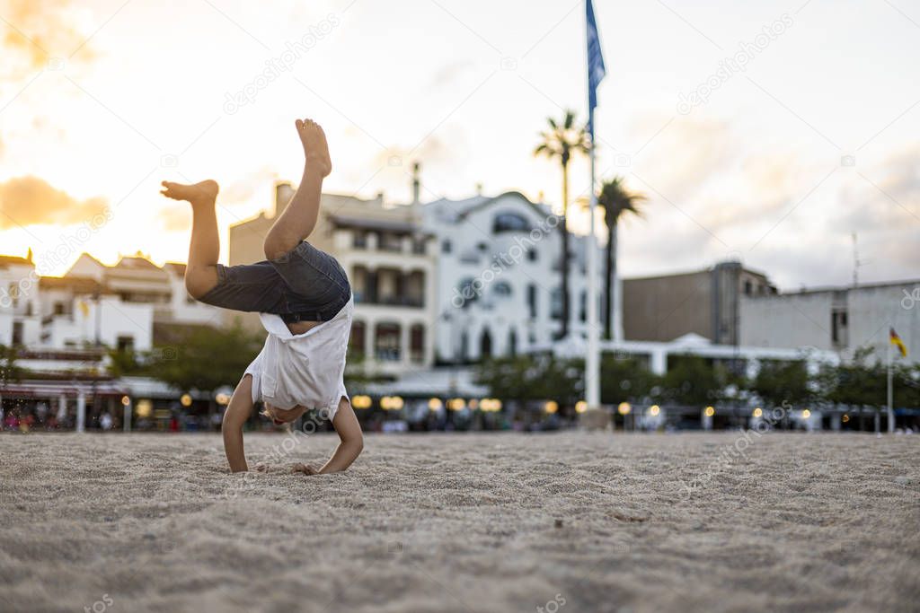 Little child making a somersault on the beach