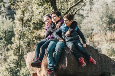 Three friends sitting together on a rock