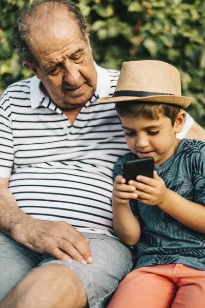 Avô e neto brincando com um telefone celular — Fotografia de Stock