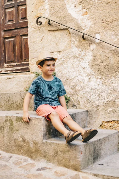 Mooie jongen zittend op de trap in een zomerdag — Stockfoto