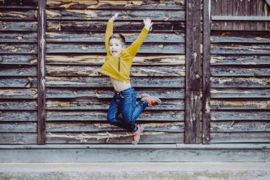 Cute child jumping and laughing with a wooden background