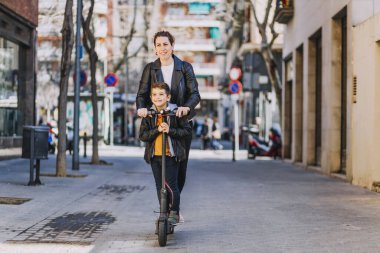 Anne ve oğlu elektrikli scooter kullanıyor.