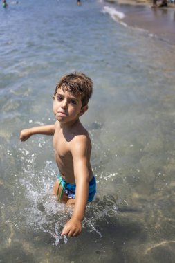 Sahilde kameraya bakan saldırgan bir çocuk.