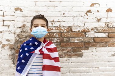 Amerikan bayrağı ve maskesi olan küçük bir çocuk.