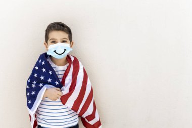 Amerikan bayrağı ve maskesi olan küçük bir çocuk.