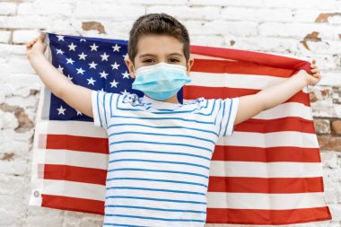 Amerikan bayrağı ve maskesi olan küçük bir çocuk.