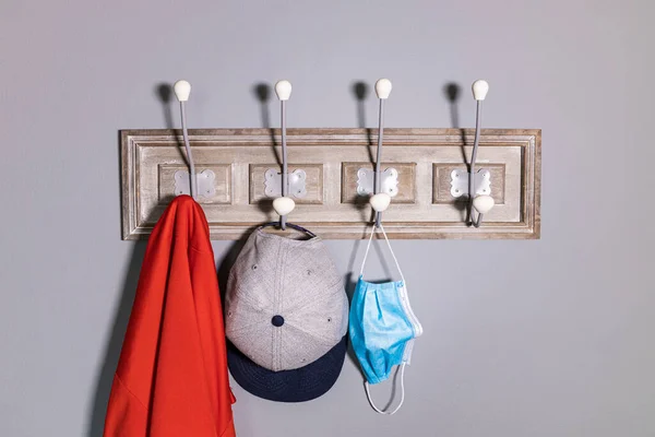 Coat rack with a jacket, a cap and a safety mask.