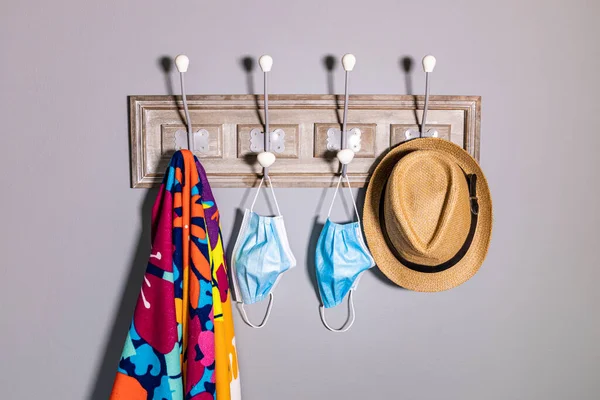 Coat rack with a beach towel, hat and a safety mask