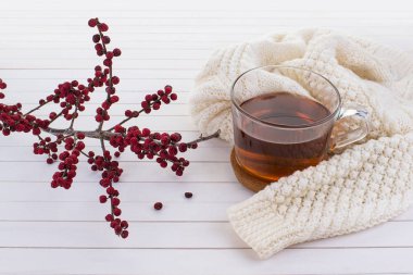 Eski beyaz ahşap arka planda, örgü süveterli bir fincan çay.