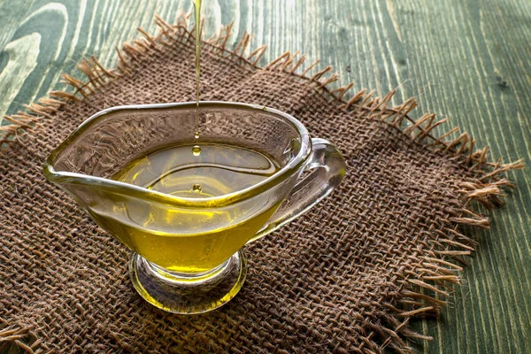 Pouring hemp oil in a glass bowl and hemp seeds in a wooden spoon on a green hemp leaf background, CBD Hemp oil — Stock Photo, Image