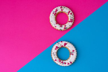 Cilalı halka şekilli rulolardan, renkli kalpli simitlerden oluşan yaratıcı bir düzen. Düz yatıyordu. Doğa konsepti. Kavramsal tebrik kartı. Renkli bahar arkaplanı, metin için boşluk. Moda Dekoratif Tasarımı.