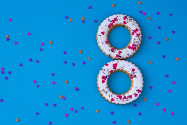 Cilalı halka şekilli rulolardan, renkli kalpli simitlerden oluşan yaratıcı bir düzen. Düz yatıyordu. Doğa konsepti. Kavramsal tebrik kartı. Renkli bahar arkaplanı, metin için boşluk. Moda Dekoratif Tasarımı.