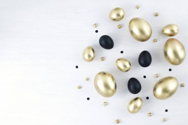 Asgari altın yumurta paskalya konsepti. Beyaz ahşap arka planda paskalya altın ve siyah yumurtaları. Paskalya bayramında düzdü. Metin için kopyalama alanı olan mutlu paskalya kartları