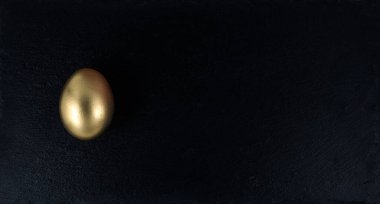 Minimal gold eggs easter concept. Stylish easter golden egg with black stone tray, white wooden background. Flat lay trendy easter. Happy easter card.Copy space for text on black board