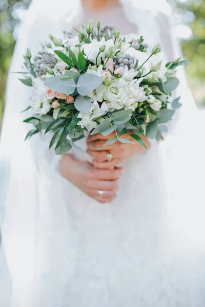 Die Braut hält den Brautstrauß in den Händen — Stockfoto