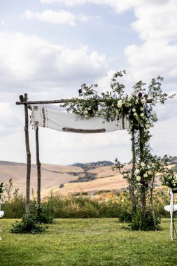 Toskana 'daki villanın arka bahçesinde okaliptüs kompozisyonları ve çiçeklerle süslenmiş ahşap kemer var.