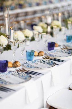 Pamuk ve çiçek kompozisyonu ile süslenmiş ziyafet masası, bardaklar ve tabaklar masaya konur